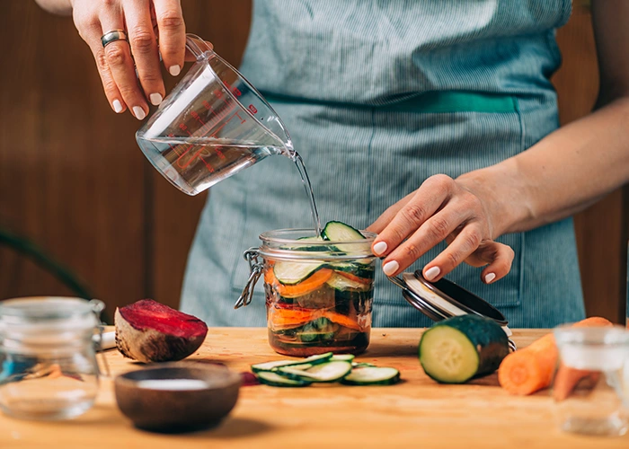 Lactofermentation : préparation de légumes coupés en bocal avec saumure et conservation de surplus de serres